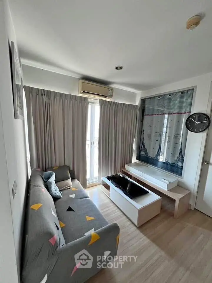 Cozy living room with modern decor and natural light, featuring a stylish sofa and air conditioning.