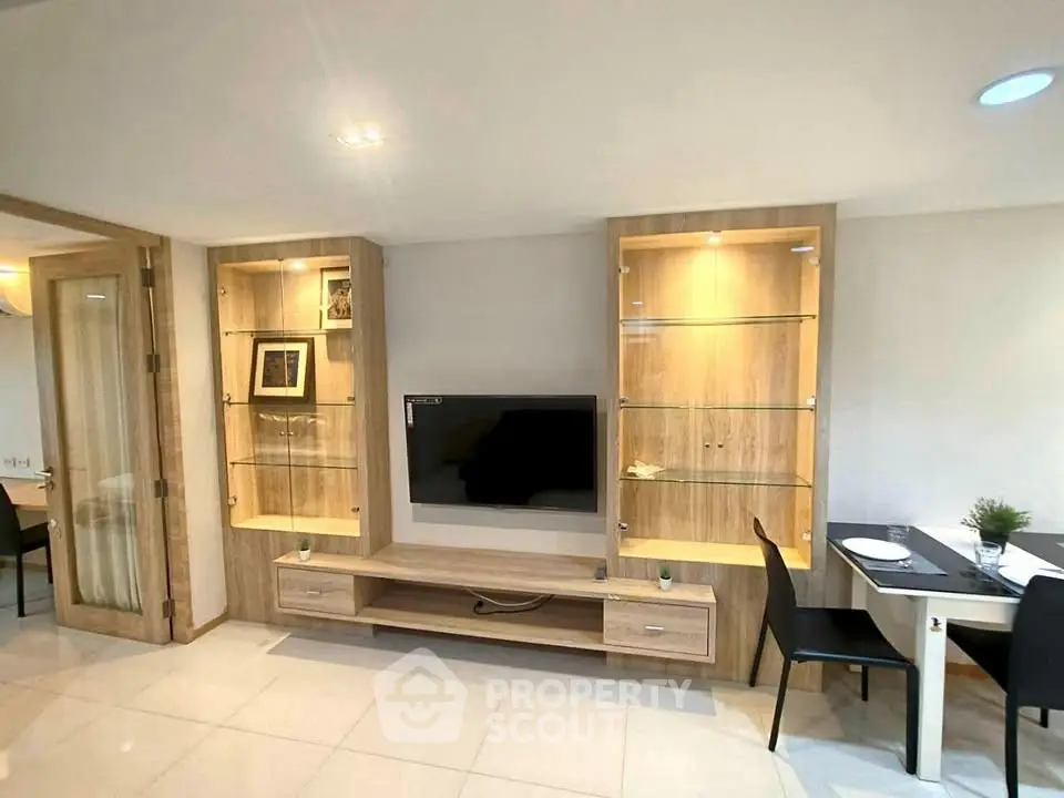 Modern living room with built-in wooden shelves and sleek TV setup.