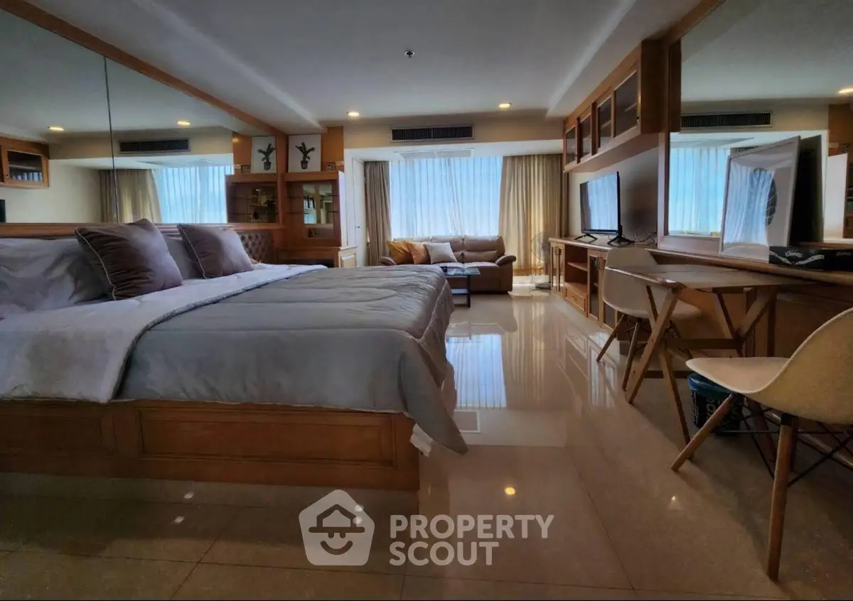 Luxurious bedroom with elegant decor and spacious layout, featuring a cozy seating area and large windows.