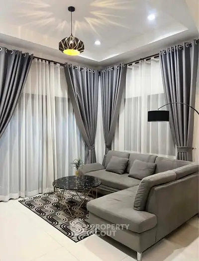 Elegant living room with modern gray sectional sofa, stylish curtains, and chic lighting.