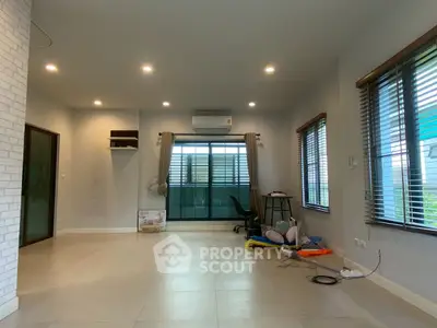 Spacious living room with large windows and modern lighting, perfect for family gatherings.