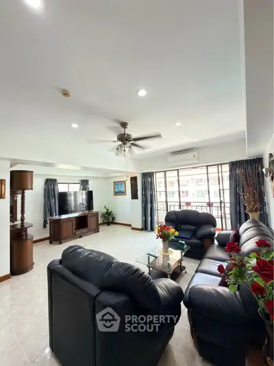 Spacious living room with leather sofas and large windows offering natural light.