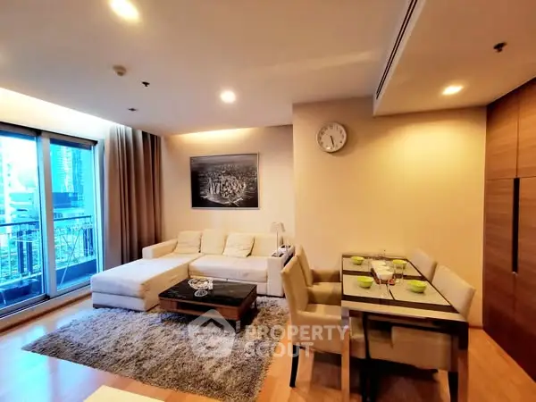 Modern living room with cozy sofa and dining area, featuring city view balcony.