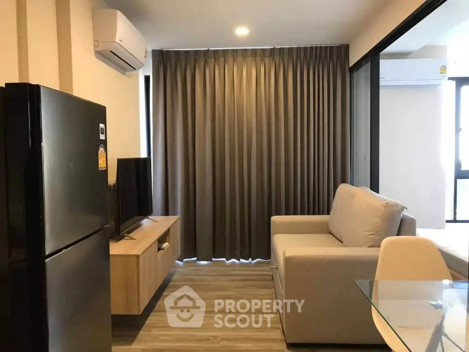 Modern living room with sleek furniture and large window, featuring air conditioning and stylish decor.