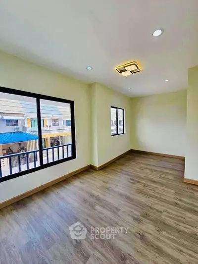 Spacious and bright room with large windows and modern lighting, perfect for a cozy living space.