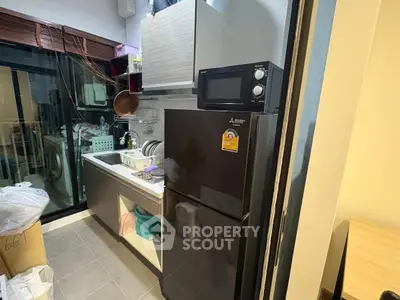 Modern kitchen with sleek black fridge and microwave, featuring a compact layout and stylish cabinetry.