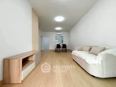 Spacious modern living room with sleek wooden flooring and cozy sofa, perfect for relaxation and entertaining.