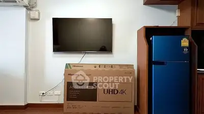 Modern living room with wall-mounted TV and new fridge, showcasing sleek interior design.