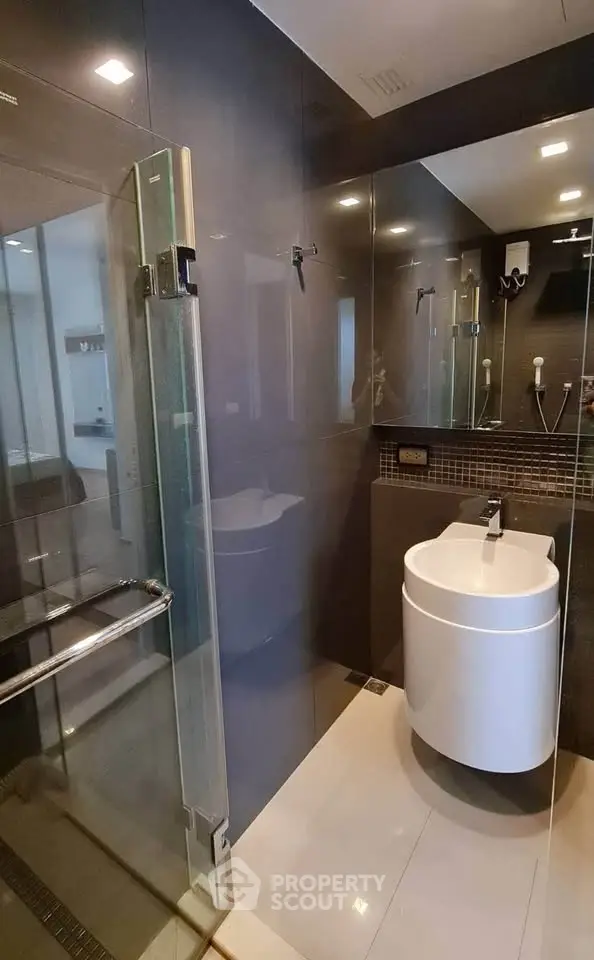 Modern bathroom with sleek glass shower and stylish sink in contemporary apartment.
