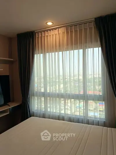 Spacious bedroom with large window offering stunning city views, perfect for urban living.