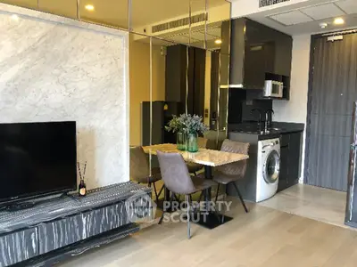 Modern living room with sleek kitchen and washing machine, stylish dining area, and elegant decor.