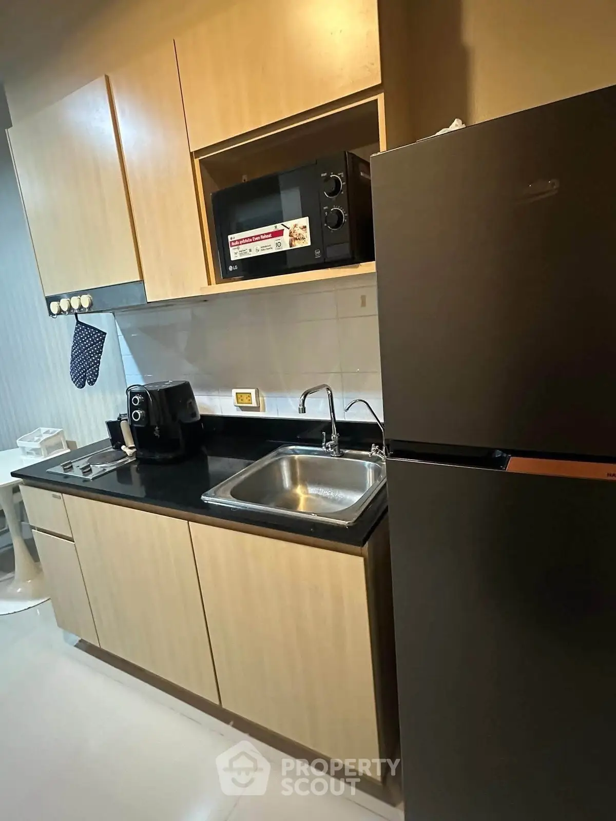 Modern kitchen with sleek cabinets, microwave, and refrigerator in a compact layout.