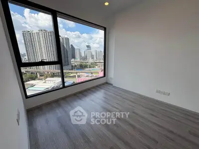 Spacious empty room with large window offering stunning cityscape views, perfect for modern living.