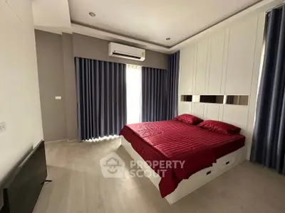 Modern bedroom with red bedding, sleek design, and ample natural light