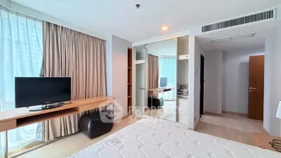 Spacious bedroom with modern furnishings and large mirrored wardrobe in a bright apartment.