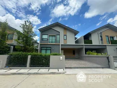 Modern two-story house with spacious driveway and lush greenery under a clear blue sky.