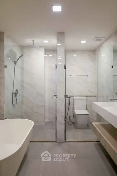 Luxurious modern bathroom with sleek design and elegant fixtures, featuring a spacious bathtub and glass shower.
