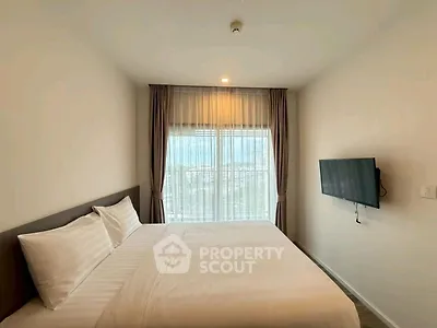 Modern bedroom with large window and wall-mounted TV in a stylish apartment.