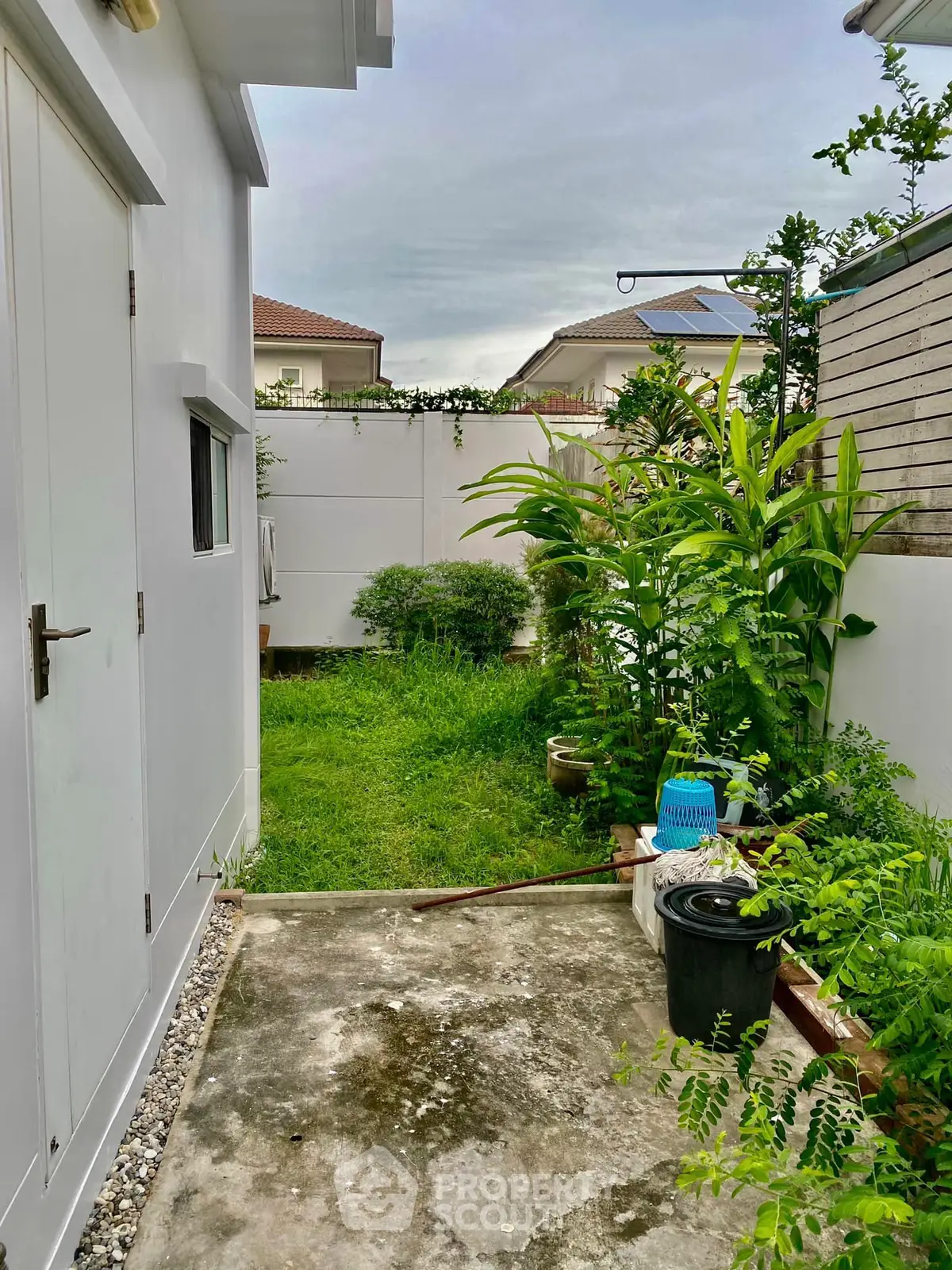 Charming backyard garden with lush greenery and paved walkway in a suburban home setting.