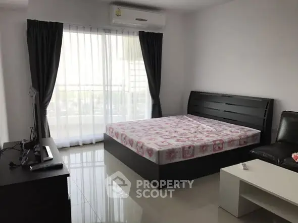Modern bedroom with sleek furniture and large window for natural light.