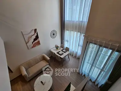 Elegant modern living room with high ceilings and large windows, featuring stylish furniture and decor.