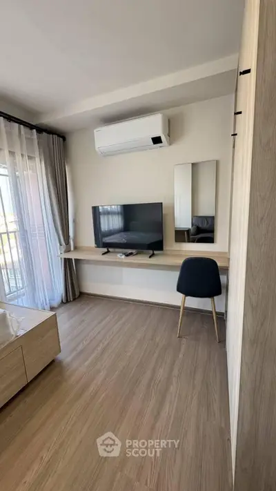 Modern living room with air conditioning and sleek wooden flooring, featuring a TV and stylish furniture.