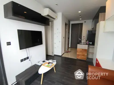 Modern apartment interior with sleek finishes, featuring a mounted TV, cozy seating, and a compact kitchen with contemporary appliances.