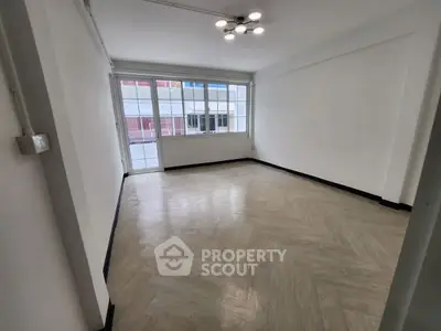 Spacious empty room with large windows and modern lighting