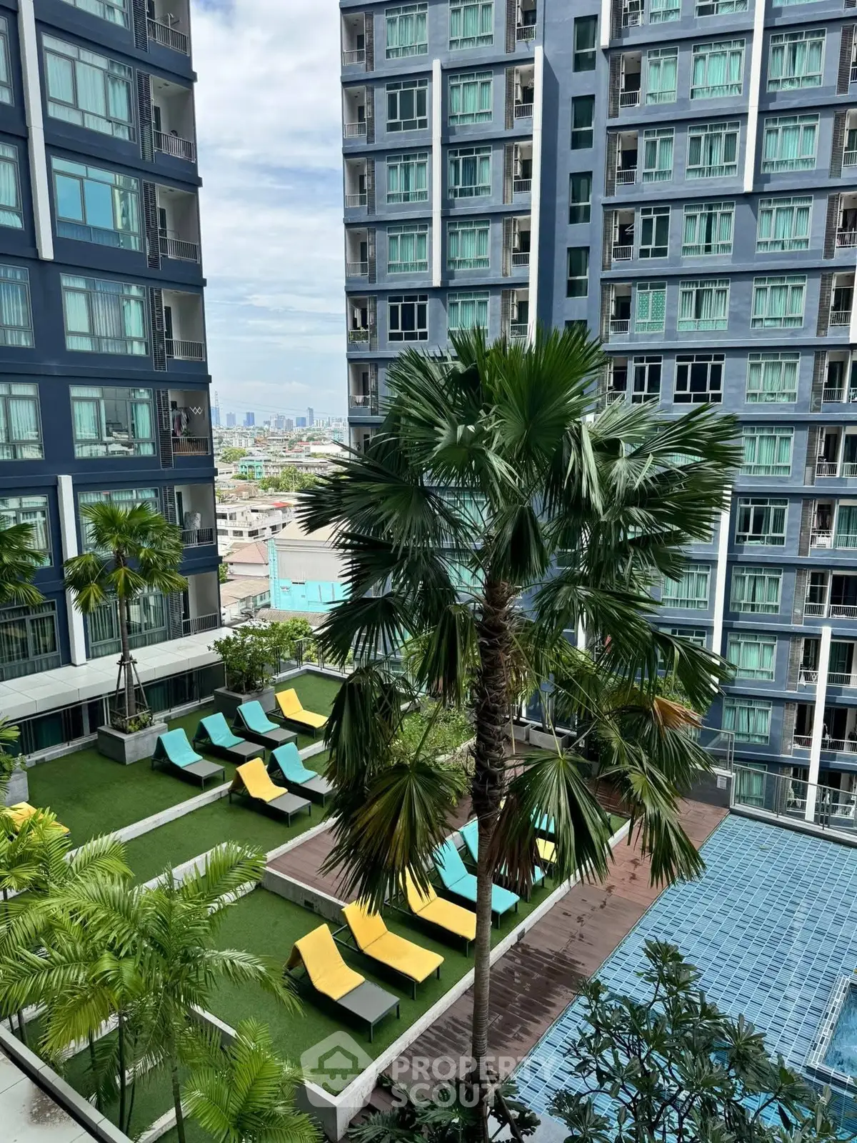 Luxurious high-rise building with pool and sun loungers offering stunning city views.