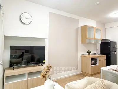 Modern living room with sleek TV setup and compact kitchen area, perfect for urban living.