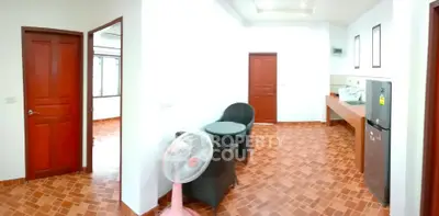 Spacious interior with modern kitchen and seating area, featuring tiled flooring and wooden doors.