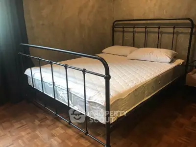 Cozy bedroom with stylish metal bed frame and parquet flooring, perfect for restful nights.