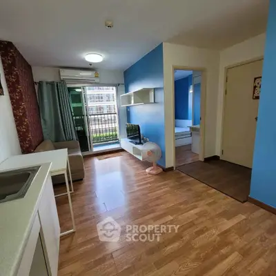 Modern living room with wooden flooring, blue accent wall, and balcony access in a stylish apartment.