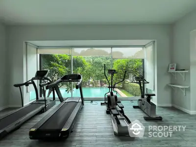 Modern gym with pool view and exercise equipment in luxury real estate property.