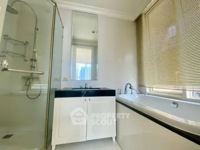 Modern bathroom with glass shower and bathtub, featuring sleek design and natural light.