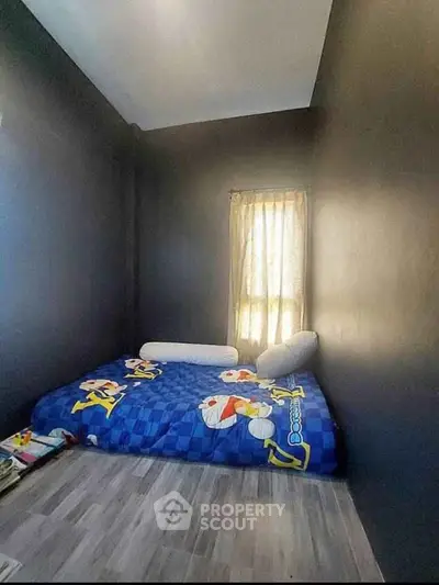 Cozy bedroom with minimalist design and natural light, featuring a playful bedspread.
