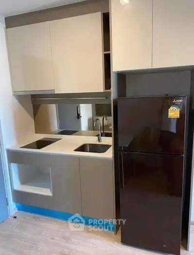 Modern compact kitchen with sleek cabinetry and built-in appliances in a stylish apartment.