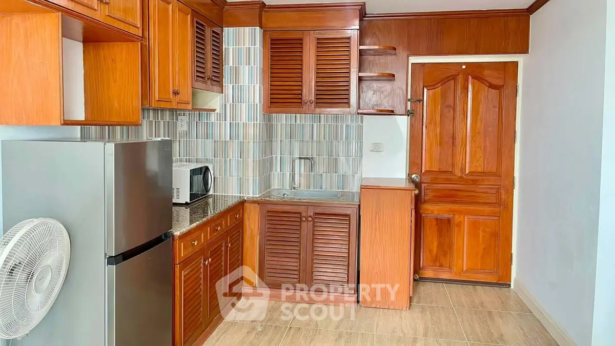 Charming kitchen with wooden cabinetry and modern appliances in cozy apartment.