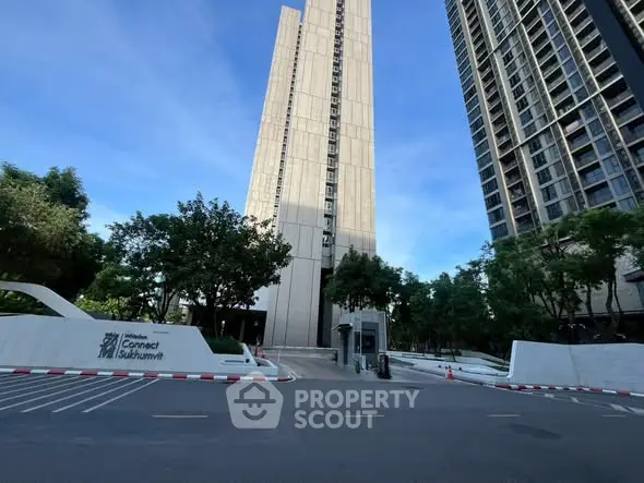 Modern high-rise building with lush greenery and spacious parking area.