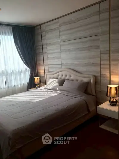 Luxurious bedroom with elegant decor and natural light, featuring a plush bed and stylish lamps.