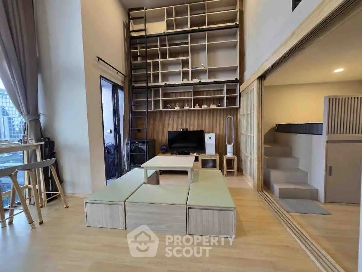 Modern living room with high ceilings and loft bed, featuring sleek storage solutions and stylish decor.