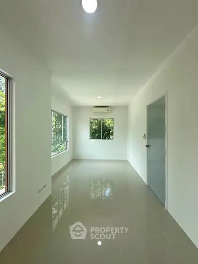 Bright and spacious room with large windows and glossy tiled floor, perfect for modern living.