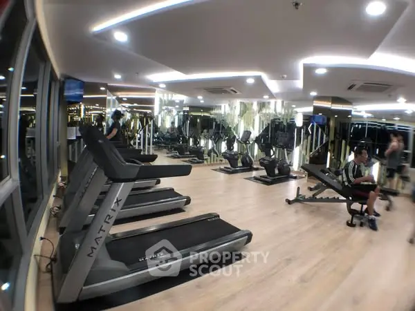 Modern gym with state-of-the-art equipment and mirrored walls in luxury apartment complex.