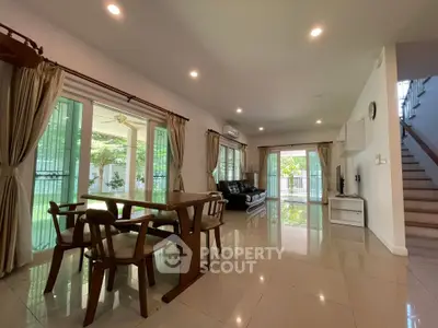 Spacious open-plan living room with dining area and large windows offering garden views.