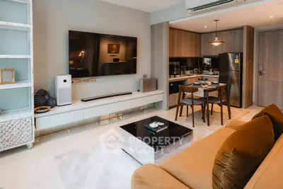 Modern living room with open kitchen, stylish decor, and large TV