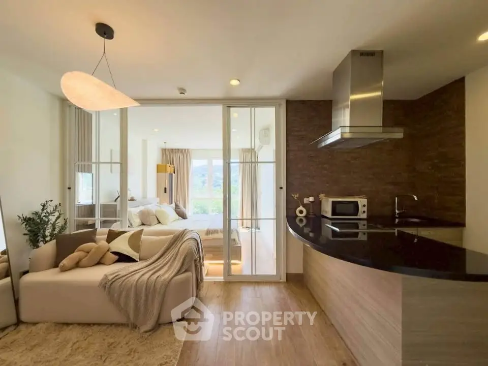 Modern open-layout living room with sleek kitchen and cozy bedroom view, perfect for urban living.