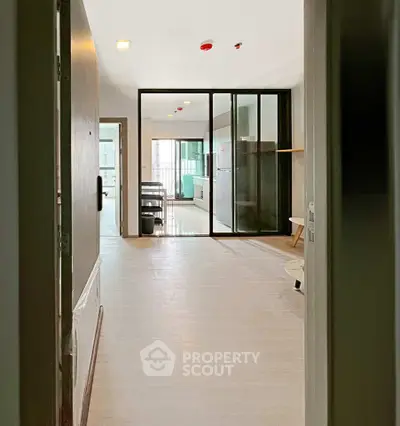 Modern apartment entrance with open layout and glass partition, leading to a bright living area.