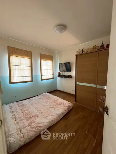 Cozy bedroom with wooden flooring, built-in wardrobe, and wall-mounted TV, perfect for a comfortable living space.