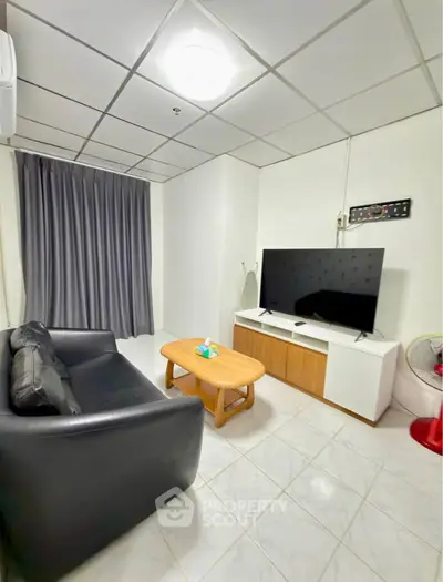 Cozy living room with modern TV setup and comfortable seating in a stylish apartment.