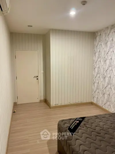 Modern bedroom with stylish wallpaper and cozy bedding in a contemporary apartment.